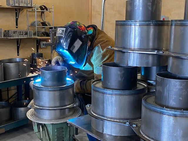 OP Machine and Fabrication welding metal components in workshop setting
